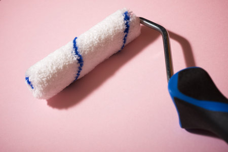 Paint roller on a pink table.の写真素材
