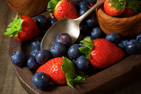 Strawberries and blueberries in wooden bowls.