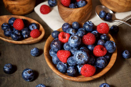 Raspberries and blueberries in wooden bowls.の写真素材