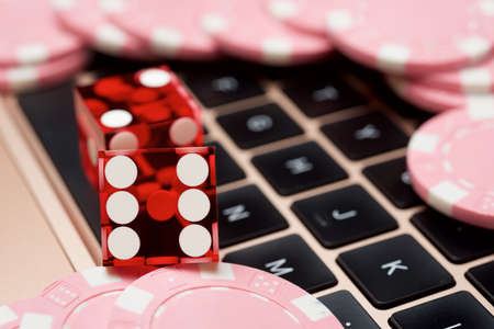 Casino chips and dices stacking on a laptop.