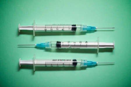 Close up of a group of syringes on a green table.