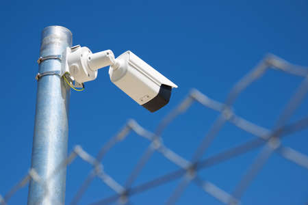 Closeup of a surveillance camera and clear sky.