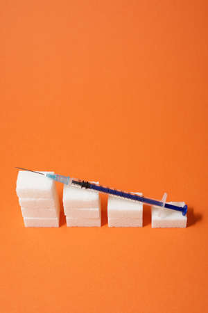 Sugar cubes and syringe on a table.の写真素材