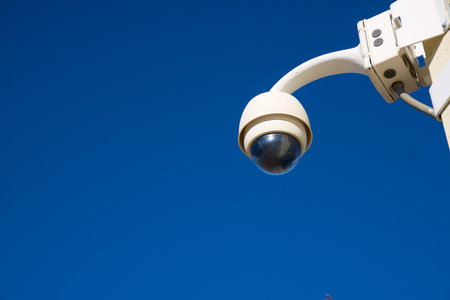 Closeup of a surveillance camera and clear sky.
