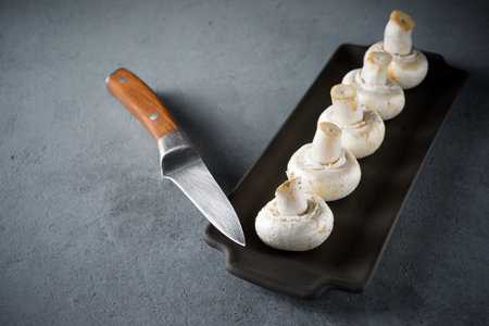 Mushrooms lined up in a black tray on a table.の写真素材