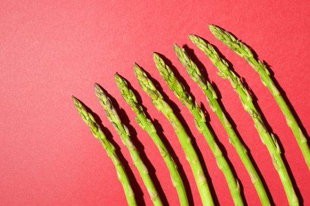 Green asparagus lined up on a red tableの写真素材
