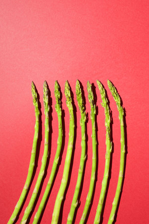 Green asparagus lined up on a red tableの写真素材