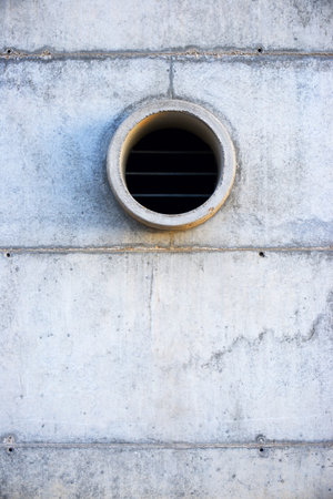 Pipe for water drainage in a concrete wall, located in a park with risk of flooding.の写真素材