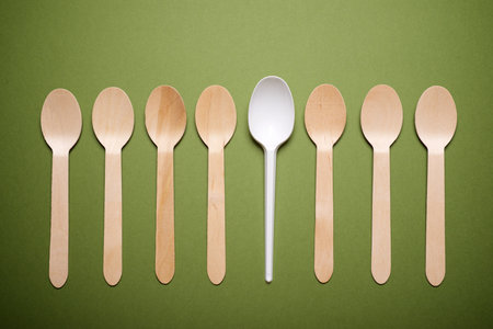 Disposable plastic and wooden spoons on a green tableの写真素材