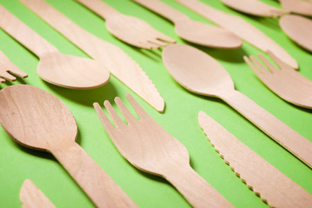 Pieces of disposable wooden cutlery on a green tableの写真素材
