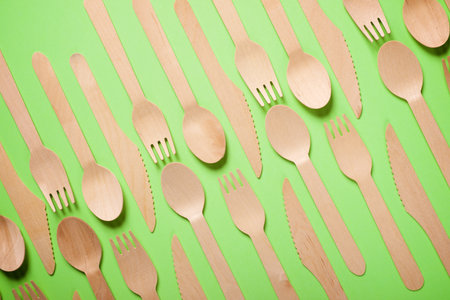 Pieces of disposable wooden cutlery on a green tableの写真素材
