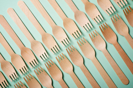 Pieces of disposable wooden forks on a green tableの写真素材