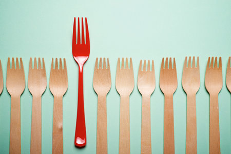 Disposable plastic and wooden forks on a green tableの写真素材