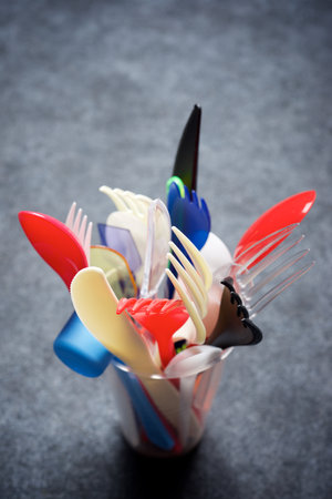 Disposable plastic cutlery in a glass on a gray tableの写真素材