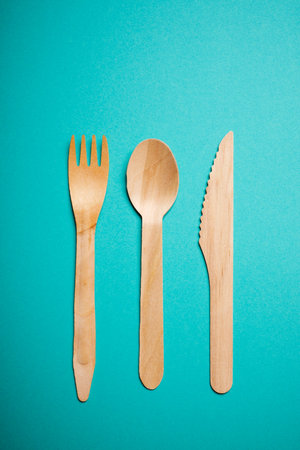 Three pieces of disposable wooden cutlery on a green tableの写真素材