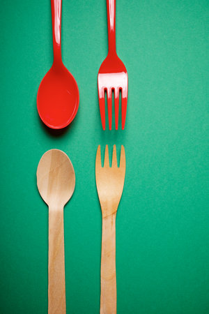 Disposable plastic and wooden forks and spoons on a green tableの写真素材
