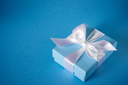 Blue gift box with a white ribbon on a table