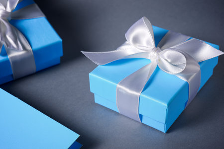 Blue gift boxes with a white ribbon on a tableの写真素材