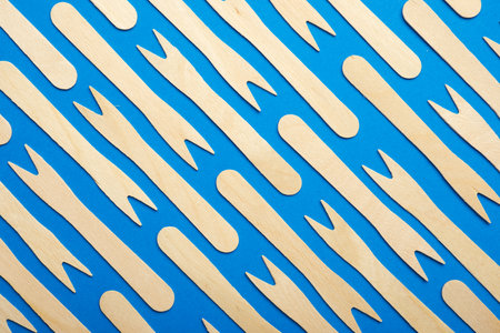 Pieces of disposable wooden forks on a blue tableの写真素材