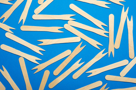 Pieces of disposable wooden forks on a blue tableの写真素材