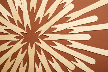 Pieces of disposable wooden forks on a brown tableの写真素材