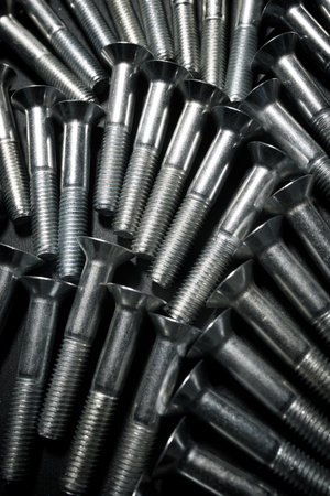 Close-up of many metal metric hexagonal screws on a table.の写真素材