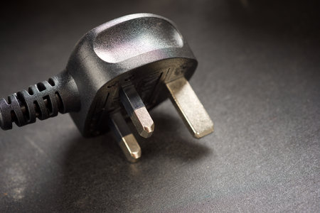 Close up on a table of a black plug used in the United Kingdom