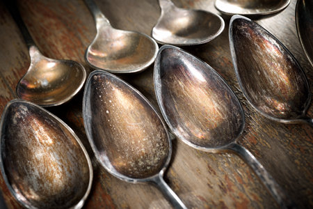 Close up of small old silver spoons on a wooden tableの写真素材