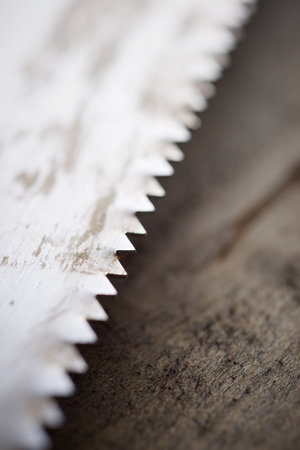 Close up of the serrated blade of an old handsaw on a work bench.の写真素材