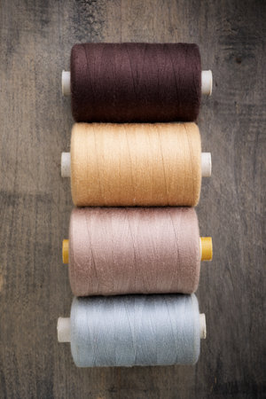 Close up of multicolored bobbins of sewing thread on a wooden table