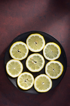 Close up of lemon slices on a ceramic dish on a red kitchen countertop.の写真素材