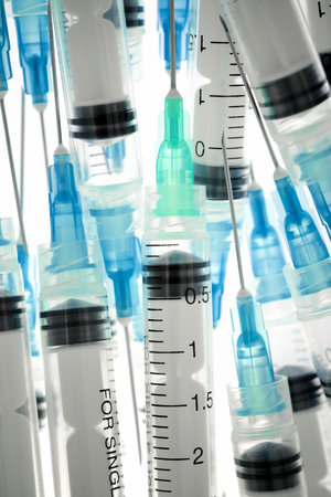 Close up of a group of hypodermic syringes on a white surfaceの写真素材