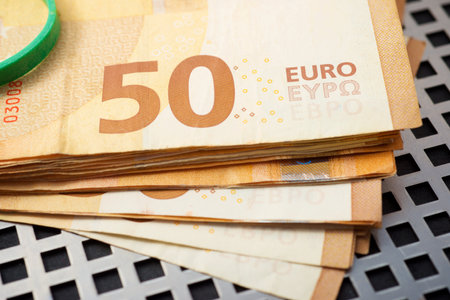 Close up of fifty-euro bills stacked on a table
