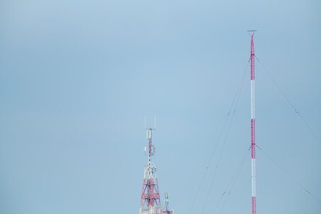 Close-up of two telecommunications towers with blue sky.の写真素材
