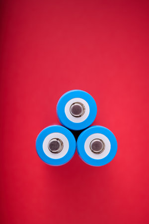 Close up of three blue rechargeable lithium batteries, size 18650, on a red table.の写真素材