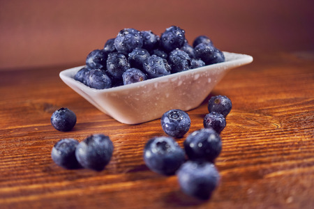 Fresh blueberries in a ceramic bowl on a wooden table.の写真素材
