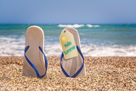 Flip flops on the beach with small stones with a tag Hello Summerの写真素材