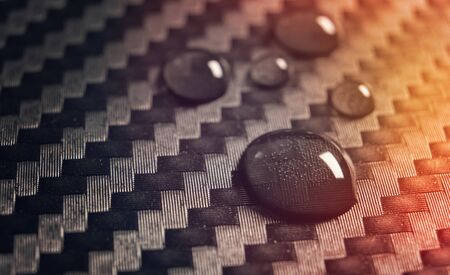 Drops of water on carbon fiber abstract background designの写真素材