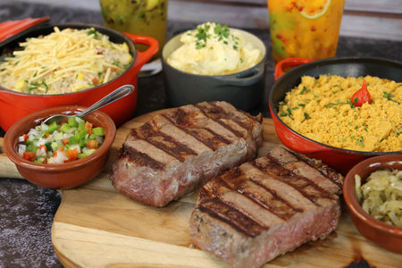 Ancho steak with grill marks and accompaniment of farofa on the side. Brazilian food.の写真素材