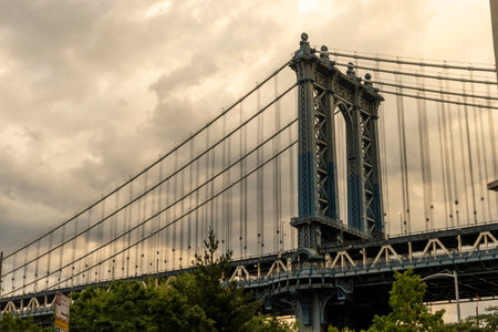 The Williamsburg Bridge stands prominently with a vibrant Manhattan skyline in the background,...