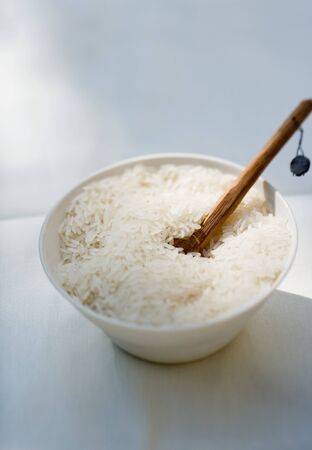 Cooked rice in ceramic plate with wooden spoonの写真素材
