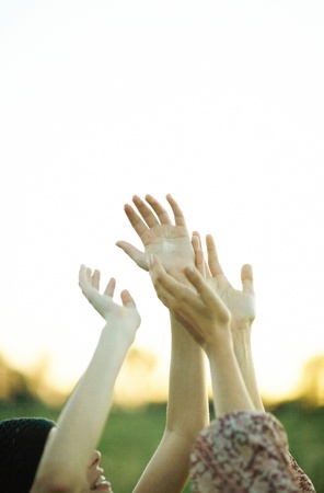 Young women reaching for dandelion seed head floating in airの写真素材