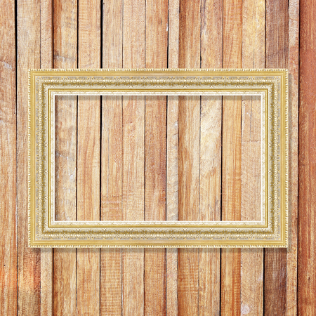 Antique gold frame on wooden wall ;. Empty picture frame on wooden wall.の写真素材