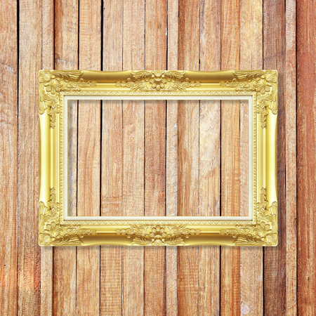 Antique gold frame on wooden wall ;. Empty picture frame on wooden wall.の写真素材