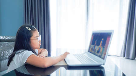 A Girl studying lesson online  from home on laptop. social distance during quarantine, self-isolation, online education concept.の写真素材