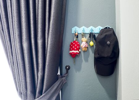 Key chain and a hat hanging to the wall of the house near the door.