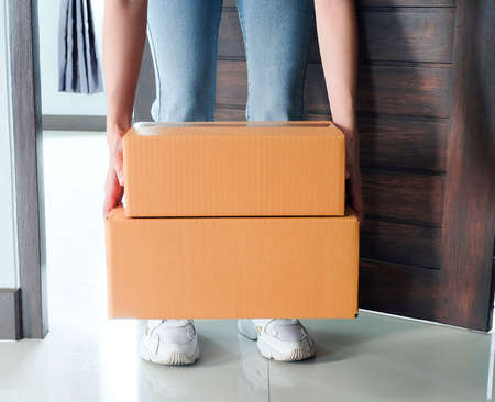 Woman pick up the parcel box to door contactless delivery during a pandemic covid. Online shopping,...