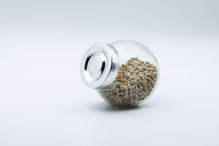 white pepper in glass bottle isolated on white background