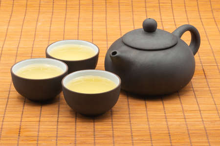 pottery Chinese teapot and teacup with tea on bamboo mat