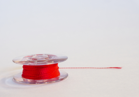 Red plastic spool of threads for sewing machine on a white background.の写真素材